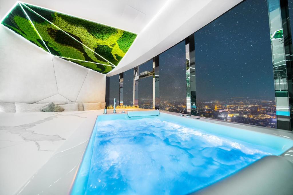 a hot tub in a bathroom with a view of the city at Apartamenty Sky Tower z Wanna Przy Oknie in Wrocław