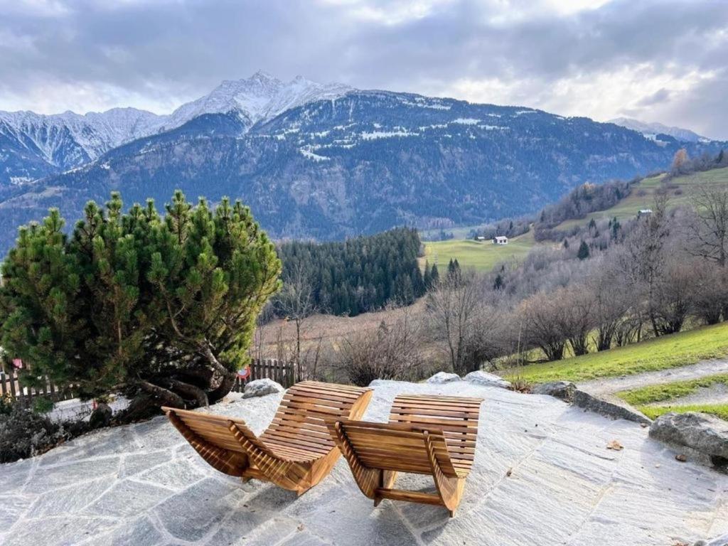 2 chaises en bois assises au sommet d'une montagne dans l'établissement Casa Campanula - No 1 Ferienhaus in Laax, à Laax