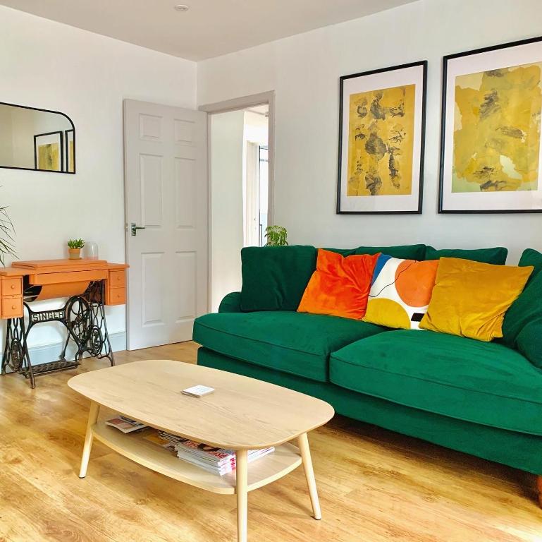a living room with a green couch and a table at The Nook - A stylish apartment with garden, near the beach in Berwick-Upon-Tweed
