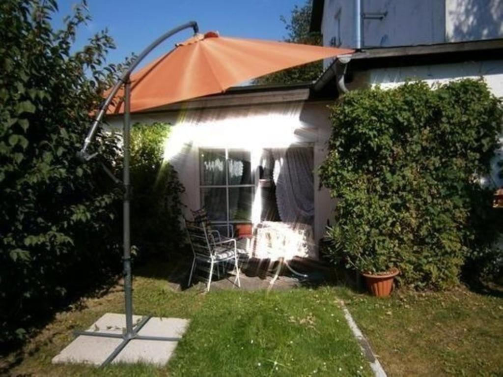 an orange umbrella in the backyard of a house at Gemütliche Wohnung in Liggersdorf mit Grill, Garten und Terrasse - b48489 in Hohenfels