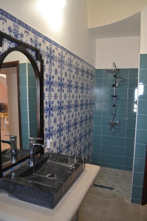 a bathroom with a sink and a mirror and a shower at Maison Rachid Djerba in El Guecheïne