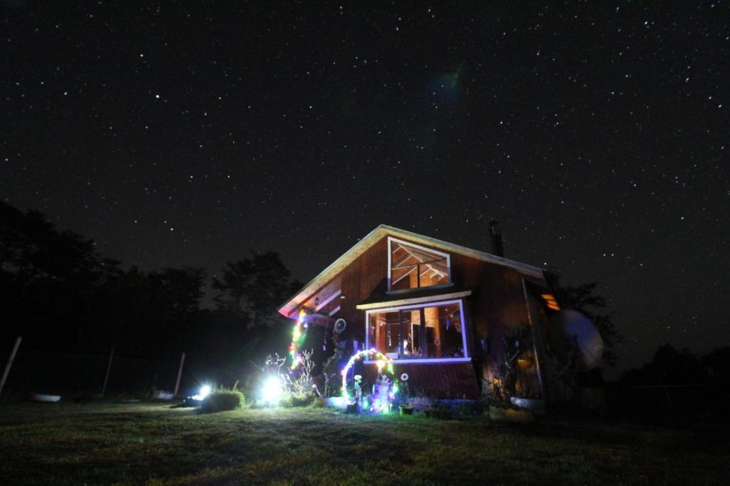 una casa decorada con luces de Navidad por la noche en Cabaña los robles, en Chonchi