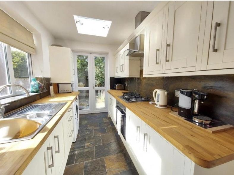 una cocina con armarios blancos y encimeras de madera en Holiday Home in Kidderminster en Kidderminster