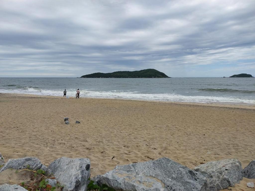 dos personas caminando en una playa cerca del océano en Casa com Piscina na Praia, en Balneário Barra do Sul