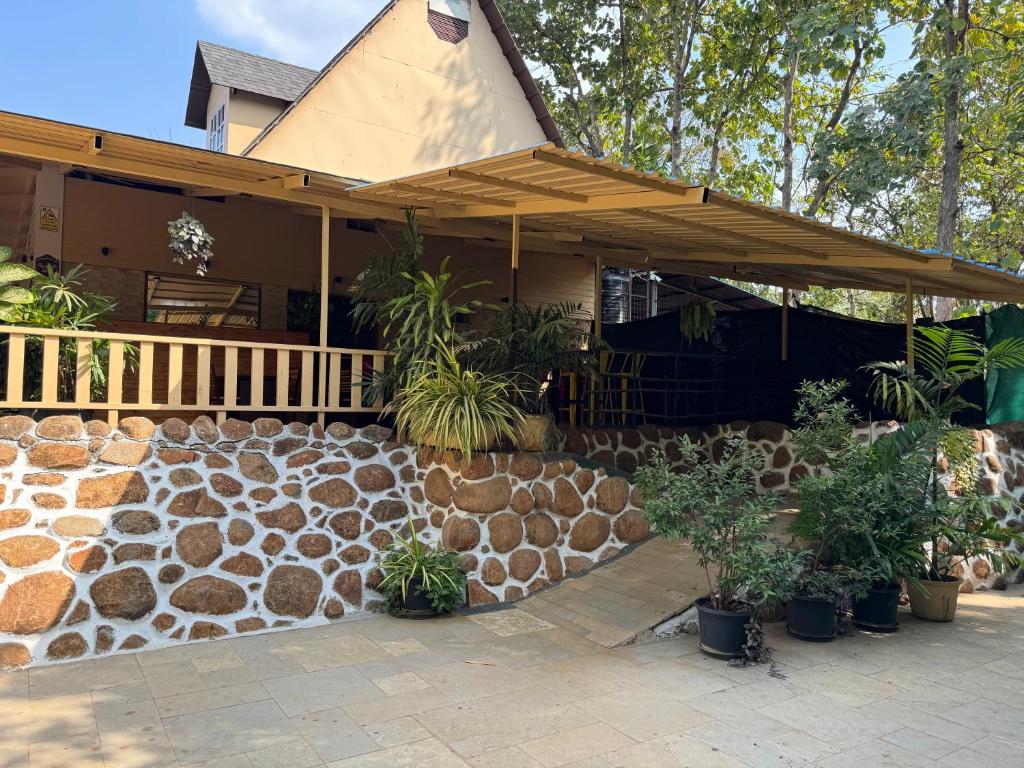 una casa con una pared de piedra y un porche con plantas en Chikoo Farm inn, en Bangalore