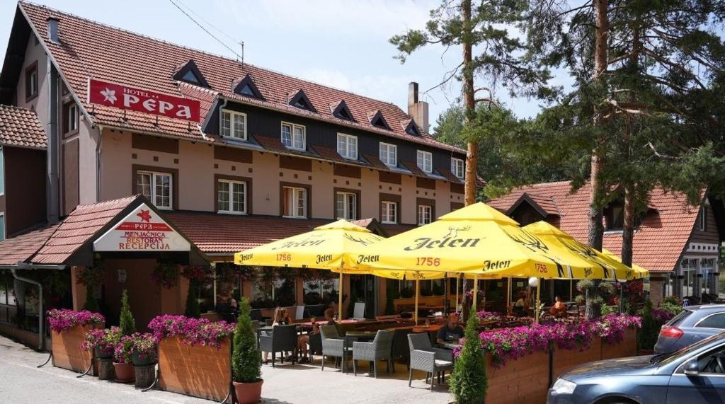 um restaurante com guarda-sóis amarelos em frente a um edifício em Hotel Pepa em Divčibare