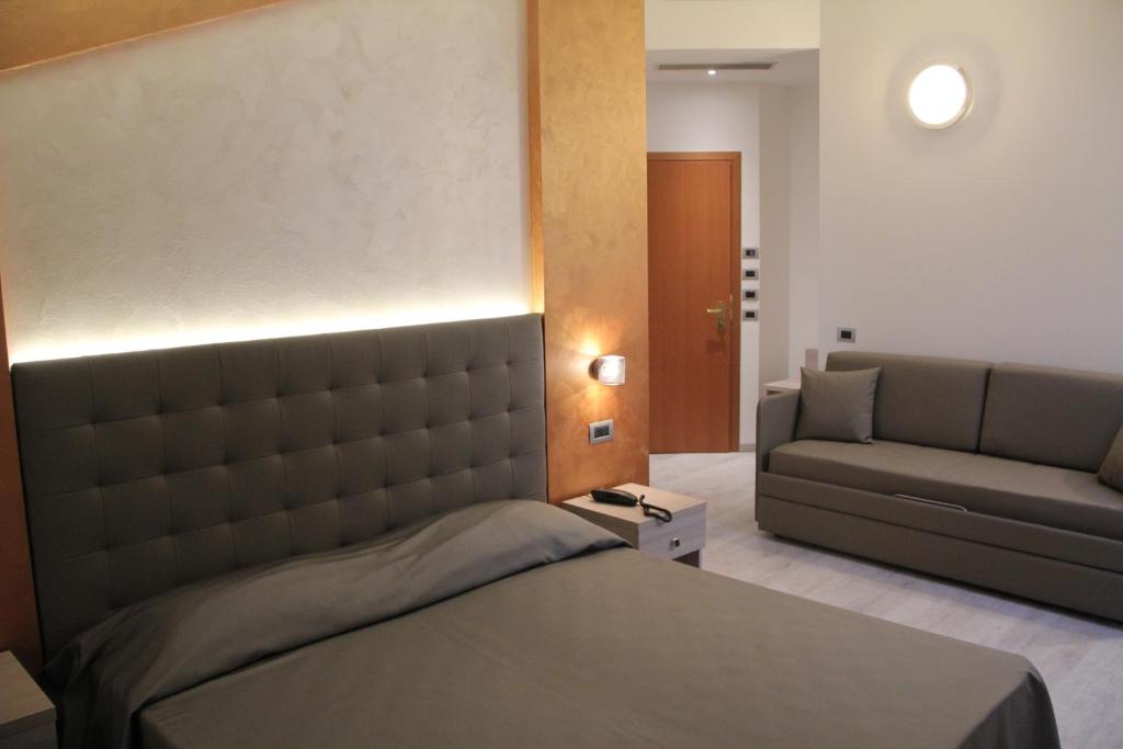 a bedroom with a bed and a couch at Hotel Gabbiano in Rimini