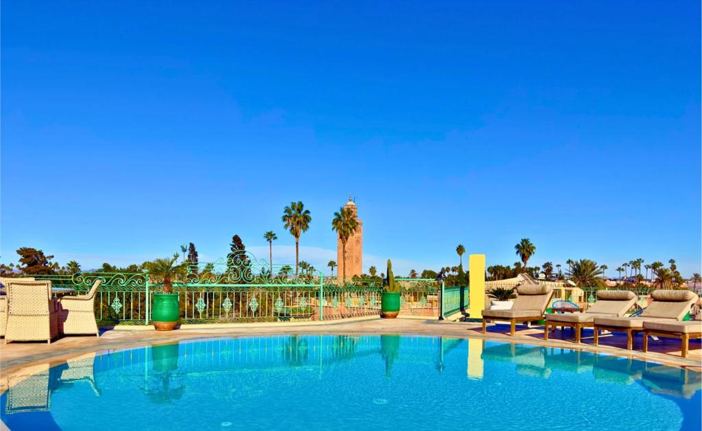a large swimming pool with chairs and palm trees at Sillage Palace Sky & Spa in Marrakesh