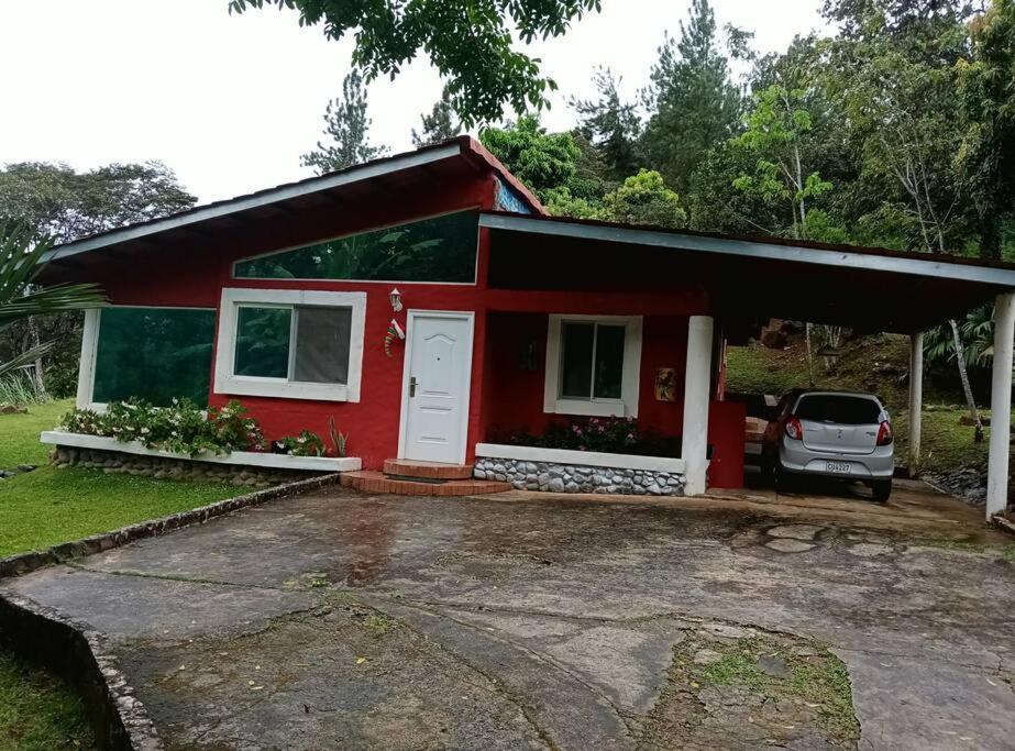 ein rotes Haus mit einem davor geparkt in der Unterkunft Cabaña Holly Water in Cerro Azul