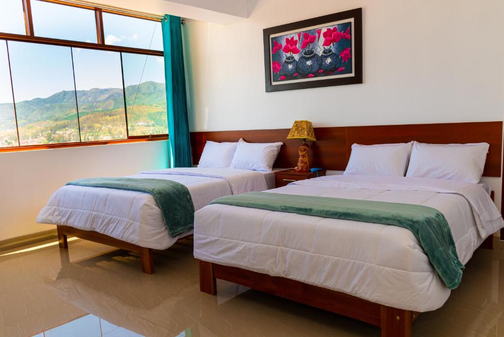 two beds in a room with two windows at HOSTAL EL MIRADOR CHACHAPOYAS in Chachapoyas
