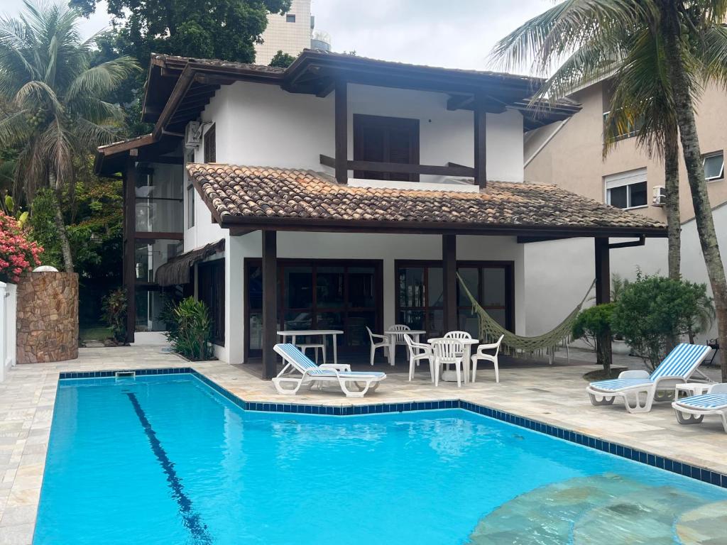 a villa with a swimming pool and a house at Casa na Praia Riviera de São Lourenço 4 Suítes para até 12 pessoas 4min a pé da Praia e 11 min a pé do Shopping in Riviera de São Lourenço
