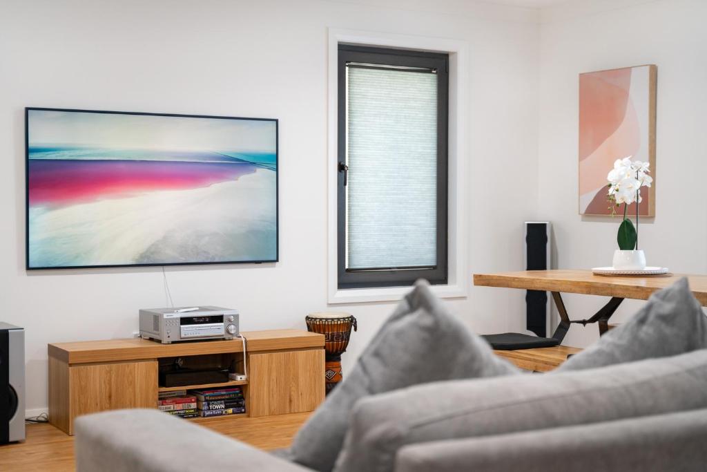 a living room with two couches and a tv at MèRose Place - Spacious Modern New in Bathurst