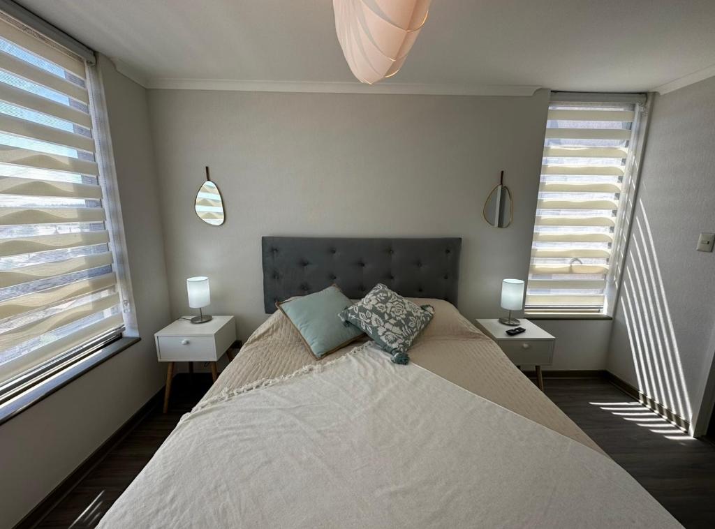 a bedroom with a large bed and two windows at Espectacular Depto. 2B+1B in Los Ángeles