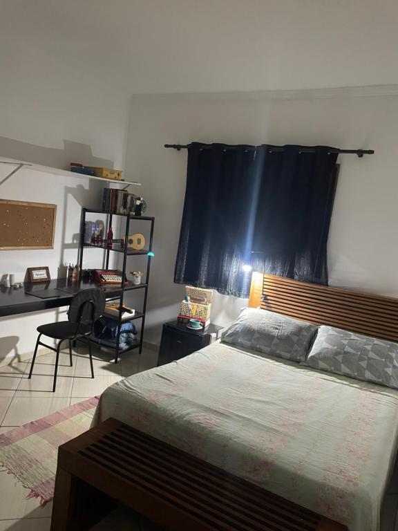 a bedroom with a bed and a desk in it at Homeoffice Central 1 quarto 1 cama de casal banheiro privativo in Alfenas