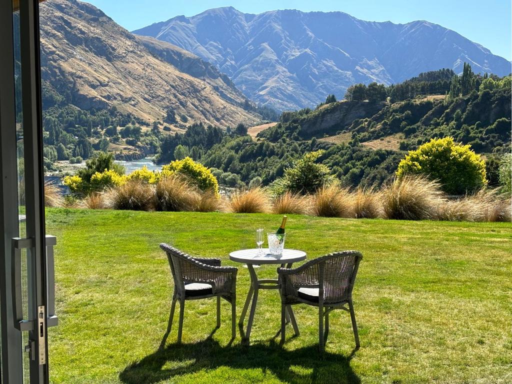 a table with two chairs and a bottle of wine on it at Tucker Beach Private Exclusive Retreat in Queenstown