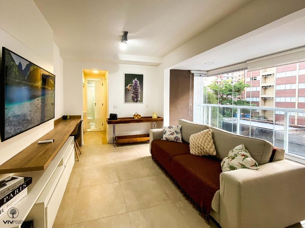 - un salon avec un canapé et une grande fenêtre dans l'établissement Premier Vivare Augusta, à São Paulo