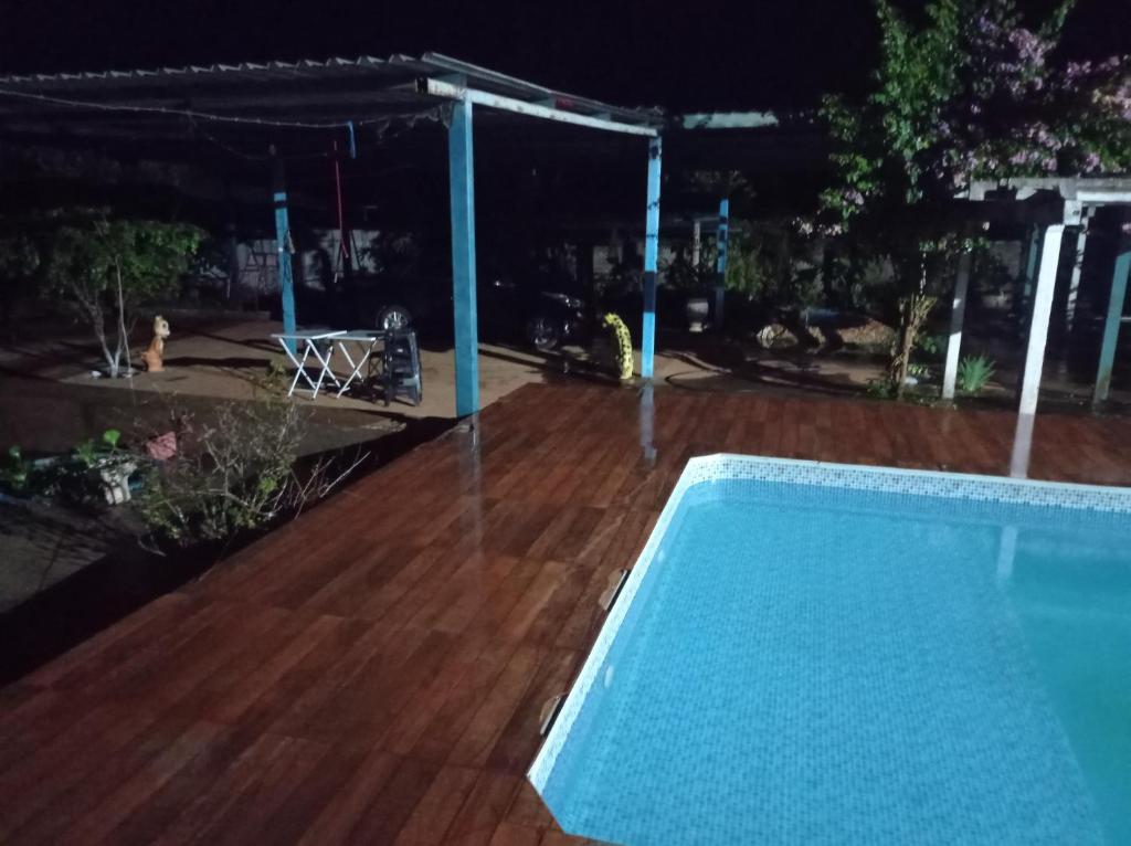 a swimming pool at night with a wooden deck at Fazendinha in Itapuranga