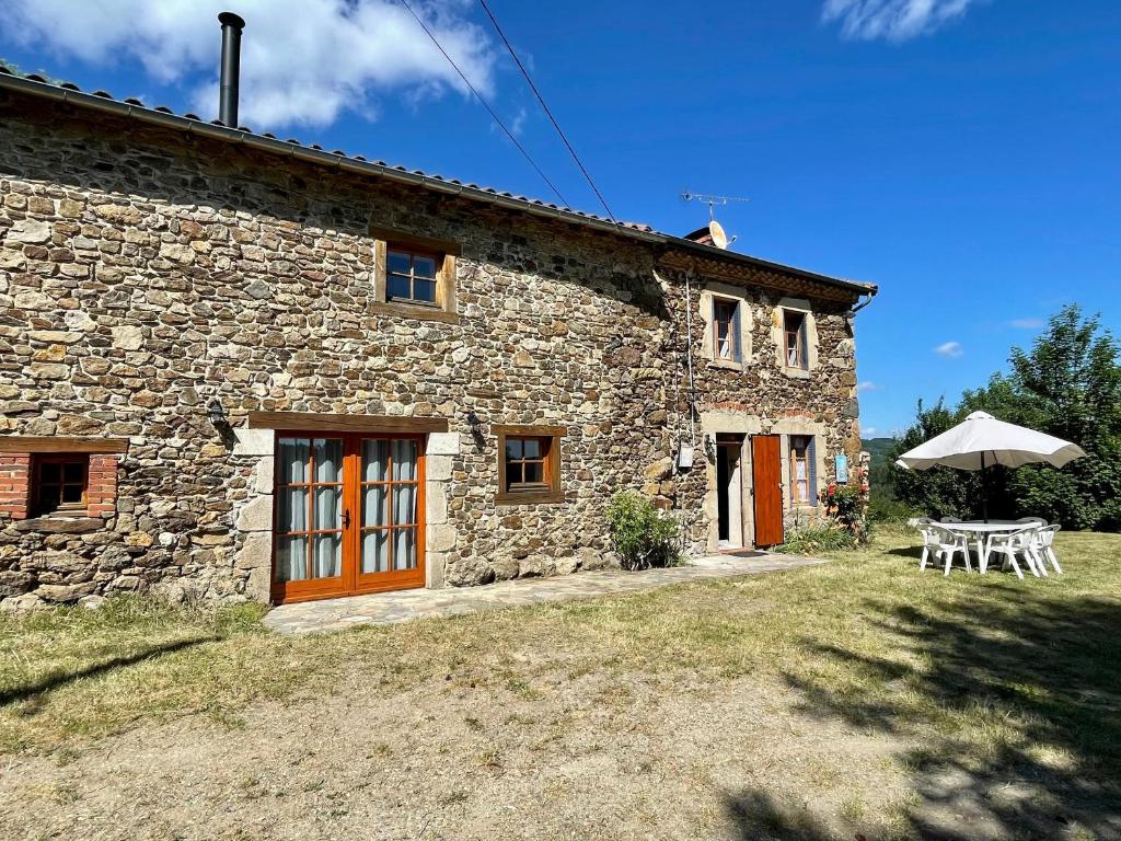 ein Steinhaus mit einem Tisch und einem Sonnenschirm in der Unterkunft Gîte Saint-Vert, 5 pièces, 7 personnes - FR-1-582-230 in Saint-Vert