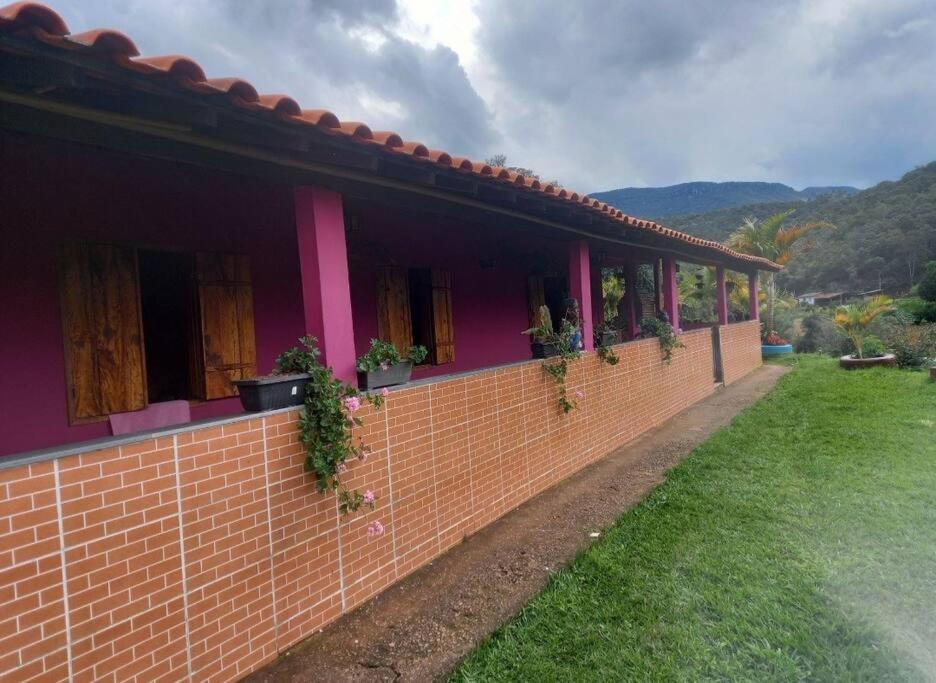 une maison rouge avec des plantes sur un mur de briques dans l'établissement Sítio do Vicente @sitiodovicenteop, à Ouro Preto