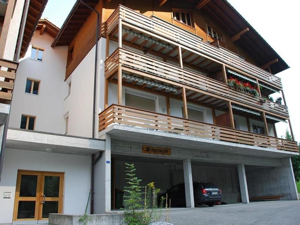 un bâtiment avec un balcon et une voiture garée devant dans l'établissement Pfingstweidli 6 Bett Wohnung - b48640, à Grindelwald