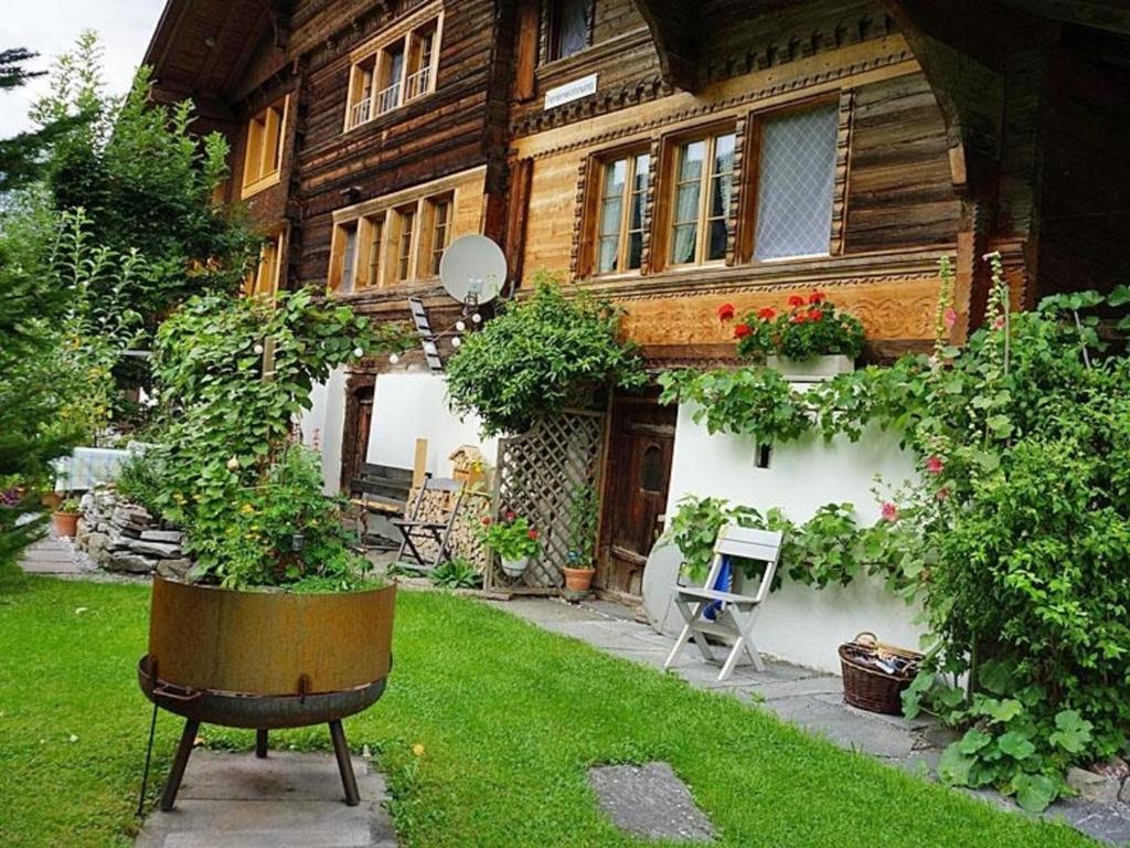 a house with a yard with a chair and flowers at Darioli 5-Bettwohnung - b48641 in Innertkirchen