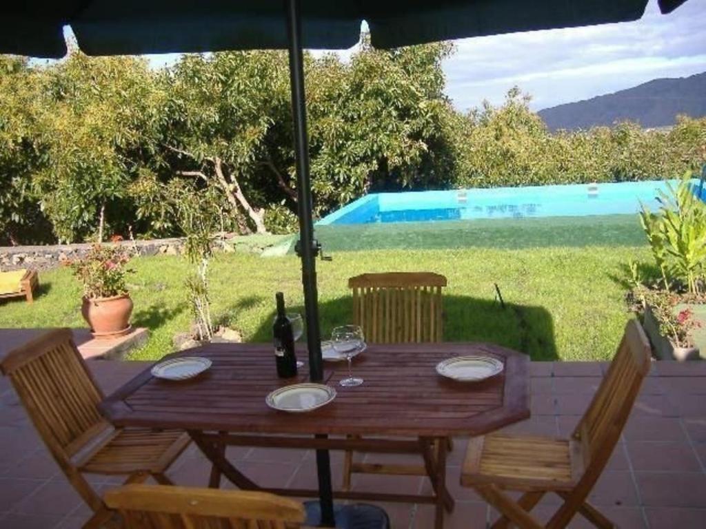 uma mesa de madeira com 2 cadeiras e uma garrafa de vinho em Großes Ferienhaus in Los Llanos De Aridane mit Privatem Pool - b48704 em Los Llanos de Aridane