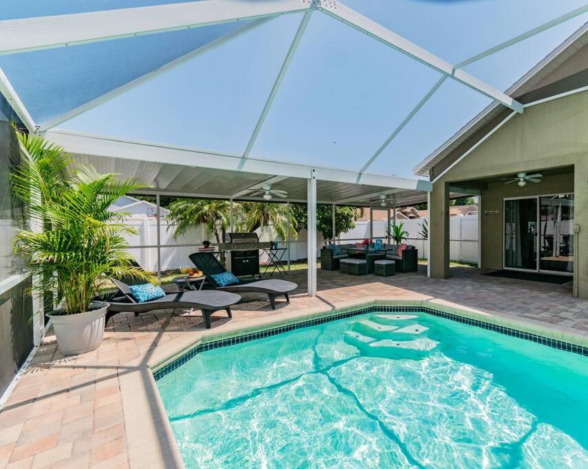 a swimming pool with an umbrella on a patio at (HGR) Poolside Paradise: Vacation retreat. (Heated Pool) in Tampa