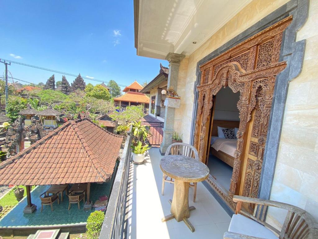 einen Balkon mit einem Bett, einem Tisch und Stühlen in der Unterkunft Wina Ubud B&B in Ubud