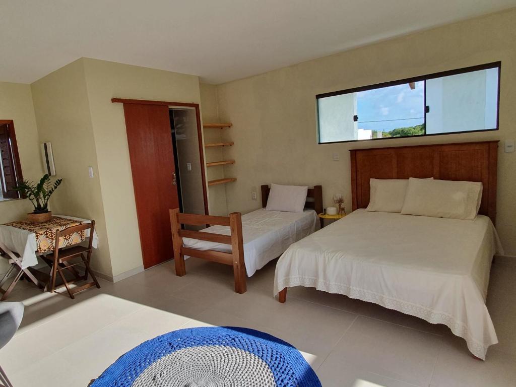 Quintal da Espera - Praia de Itacimirim في كامساري: غرفة نوم بسريرين وكرسي ونافذة