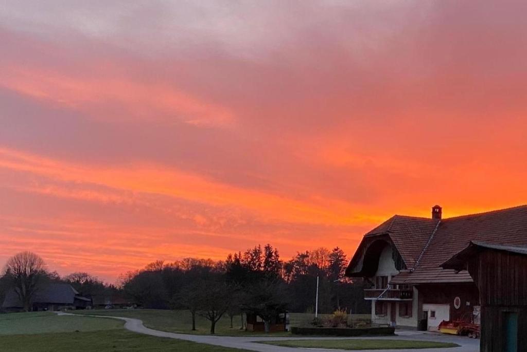 una puesta de sol sobre una casa con un edificio en La Ferme - b48766, 