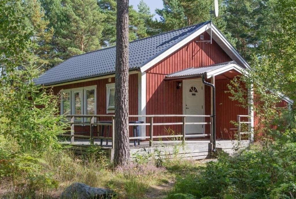 une cabine rouge avec une terrasse couverte dans les bois dans l'établissement Rustikales Landhaus mit Terrasse in einzigartiger Naturlandschaft nahe der Küste mit Anlegeplatz, ideal zum Angeln - b48729, à Loftahammar
