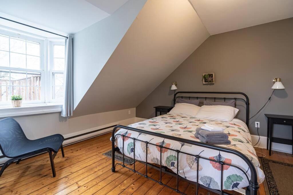 a bedroom with a bed and a chair and a window at Sunny Loft #4, Historic Home in Halifax