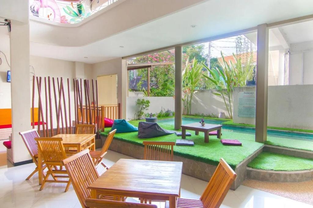 a living room with a table and chairs and a pool at Kuta Suci Guesthouse in Kuta
