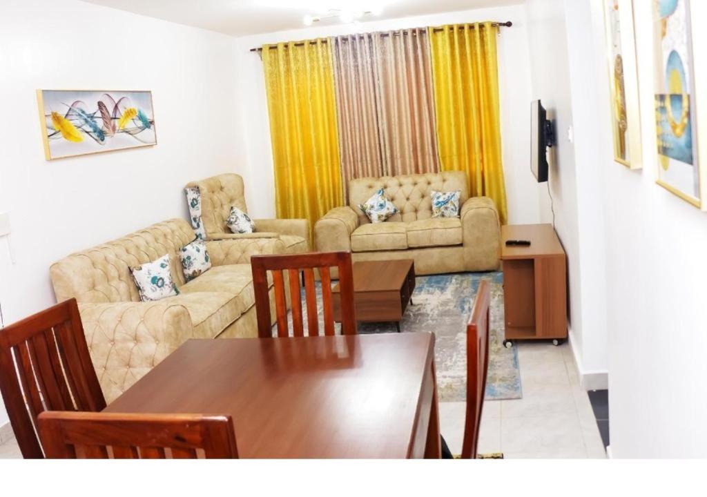 een woonkamer met een tafel en een bank bij 3 BEDROOM LIWANDO HOME at Greatwall Gardens next to Greatwall Mall, 15 Minutes from JKIA Airport With FREE WIFI & Parking, Enjoy Entire Unit in a Gated Community manned with Security 24 Hours in Athi River