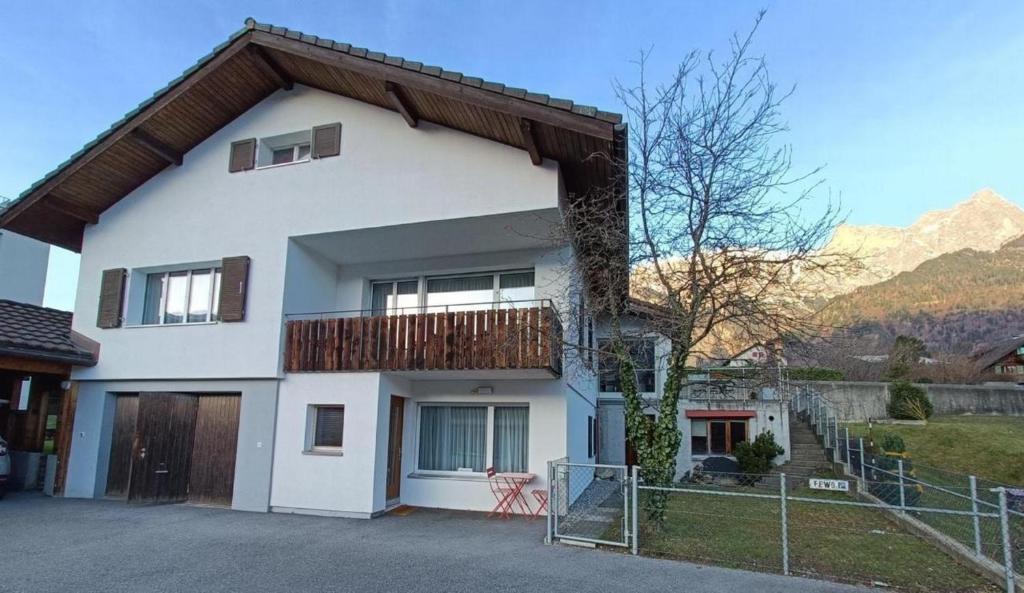 a white house with a balcony and a fence at Ferienwohnung Falknis in Maienfeld mit Blick auf die Berge - b48844 in Maienfeld