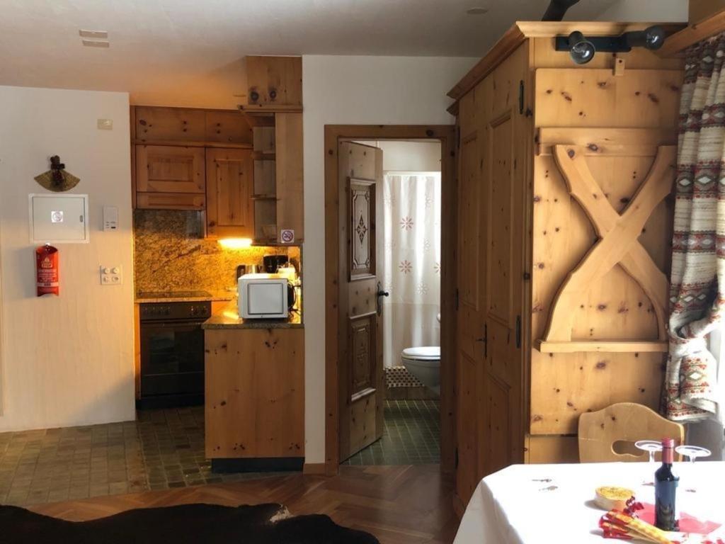 une cuisine avec des placards en bois et une porte menant à une cuisine avec un four micro-ondes dans l'établissement Chesa Trafögl - b48847, à Pontresina