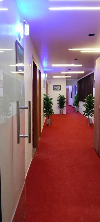 a hallway with a red carpet and potted plants at Hotel Royal Relax in Gandhinagar