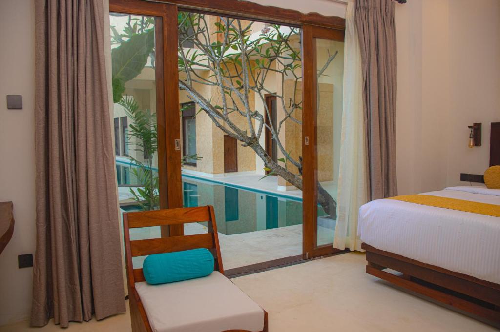 een slaapkamer met een bed en een zwembad buiten een raam bij Spicepeek Boutique Hotel CMB Airport in Katunayaka