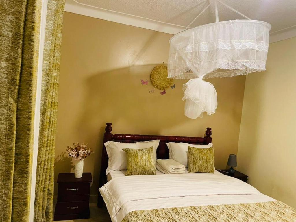 1 dormitorio con 1 cama con lámpara de araña en Muggiez Olive, Kira en Kampala