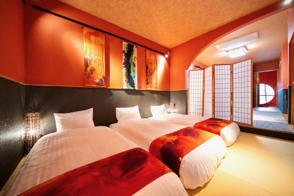 two beds in a room with orange walls at ゼロイン祇園三条 in Kyoto