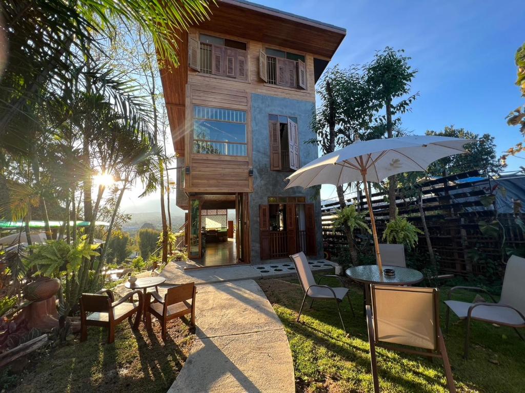 a house with a table and chairs and an umbrella at Pai Chao Kha in Pai