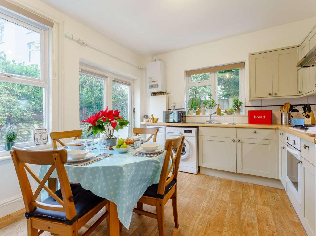 eine Küche mit einem Tisch und Stühlen sowie eine Küche mit Fenstern in der Unterkunft 2 Bed in Ventnor 86509 in Ventnor
