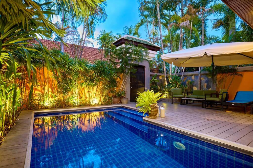 喬木提恩海灘的住宿－Bali Style Luxury View Talay POOL VILLA close to Beach & Walking Street!，一个带桌子和遮阳伞的游泳池