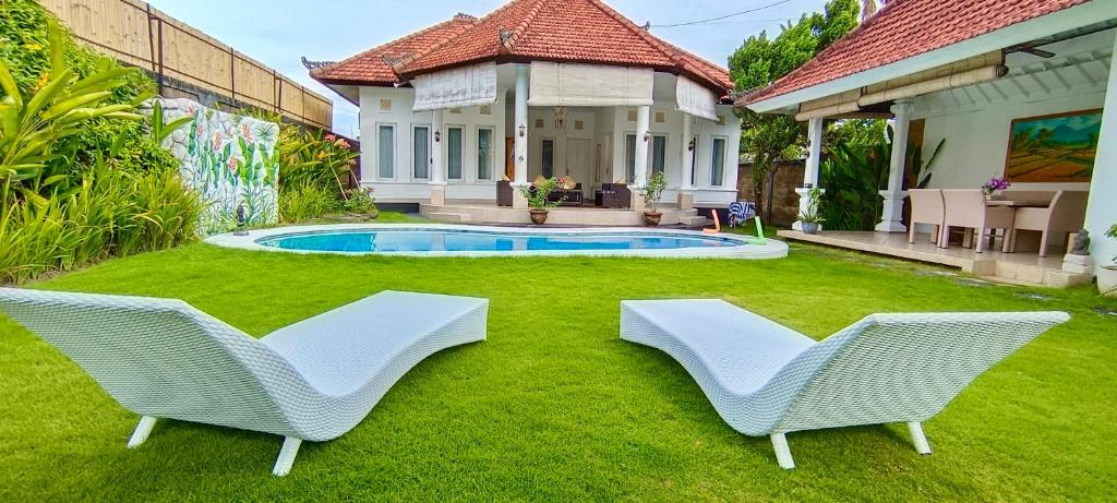 Bali Canggu 3 bdr villa Pool Garden, Discounted في كيروبوكان: كرسيان بيض يجلسون على العشب بجانب المنزل