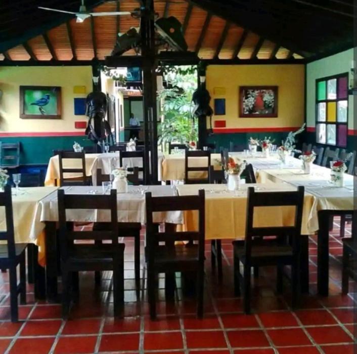 a dining room with white tables and wooden chairs at Alojamiento rural finca estrella del Quindío in Montenegro