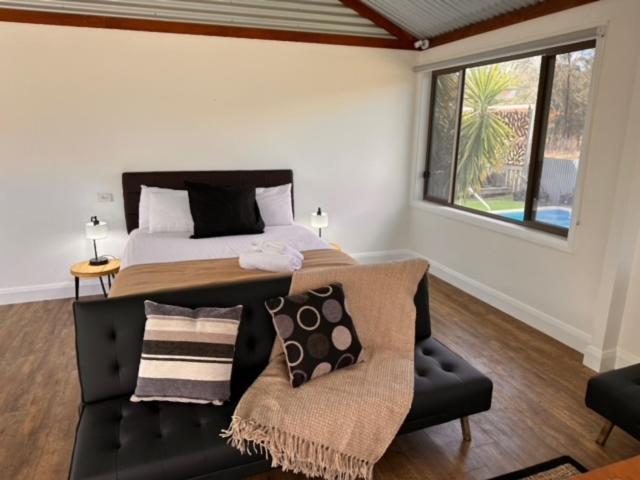 a bedroom with a large bed and a couch at Wallaby Lodges in Pokolbin