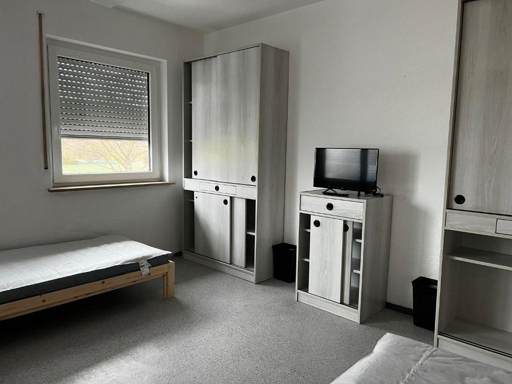 Schlafzimmer mit einem Bett und einem Flachbild-TV in der Unterkunft Geräumiges Monteurzimmer für 2 Personen in Lauda-Königshofen