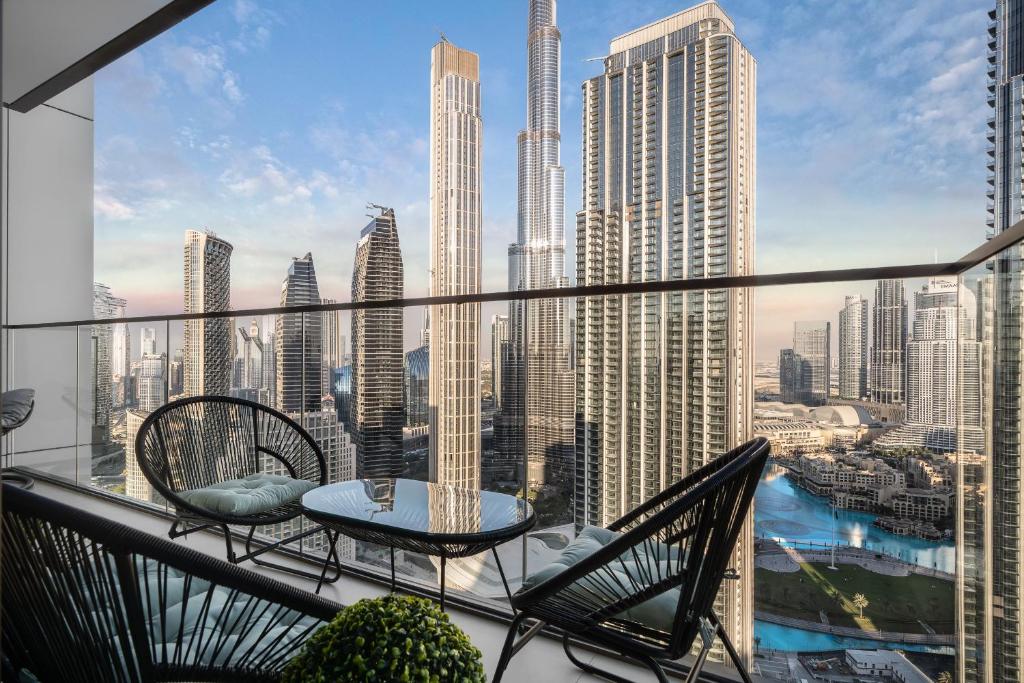 a balcony with chairs and a table and a view of a city at Sky-High Central Dubai Gem: Burj Khalifa & Fountain View in Dubai