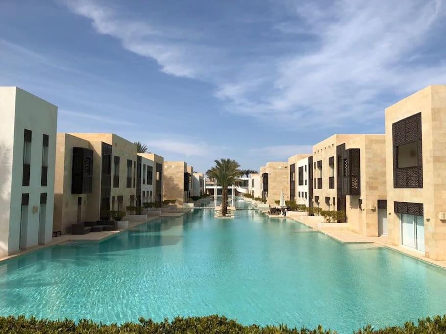 ein großer Pool mit blauem Wasser zwischen zwei Gebäuden in der Unterkunft Bright & Lovely 2 Beds Apartment in Scarab Club, El Gouna in Hurghada