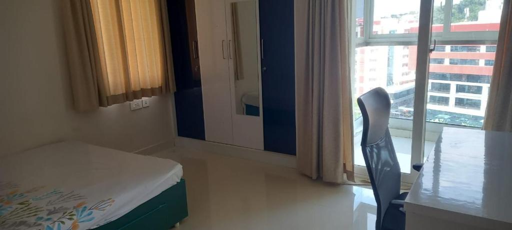 a room with a bed and a table and a window at OSKO GRAND REVIERA, 10TH FLOOR, VENPALAVATTOM, NEAR KIMS HOSPITAL, TRIVANDRUM, KERALA in Trivandrum